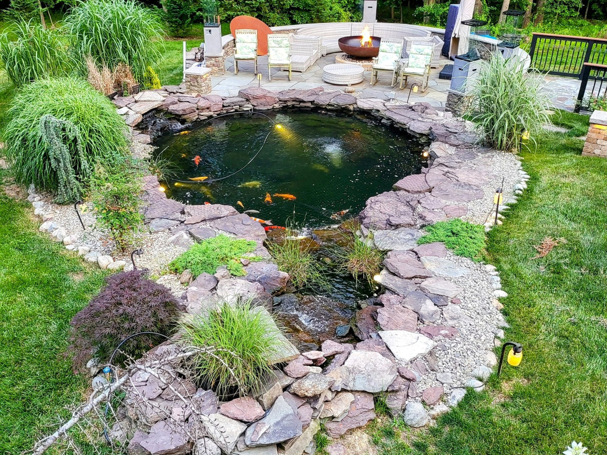 Emerick Peace's round koi pond with stone edging, ornamental grasses and a patio with a fire pit in Upper Marlboro, Maryland