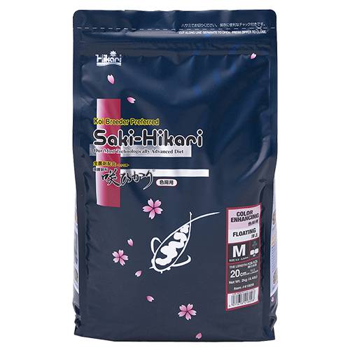 A bag of Saki-Hikari Koi Broke Flavored Advanced Diet for koi, in size M (20L). The packaging is dark navy blue with pink cherry blossom graphics, a white fish silhouette, and a red vertical accent bar on the left.
