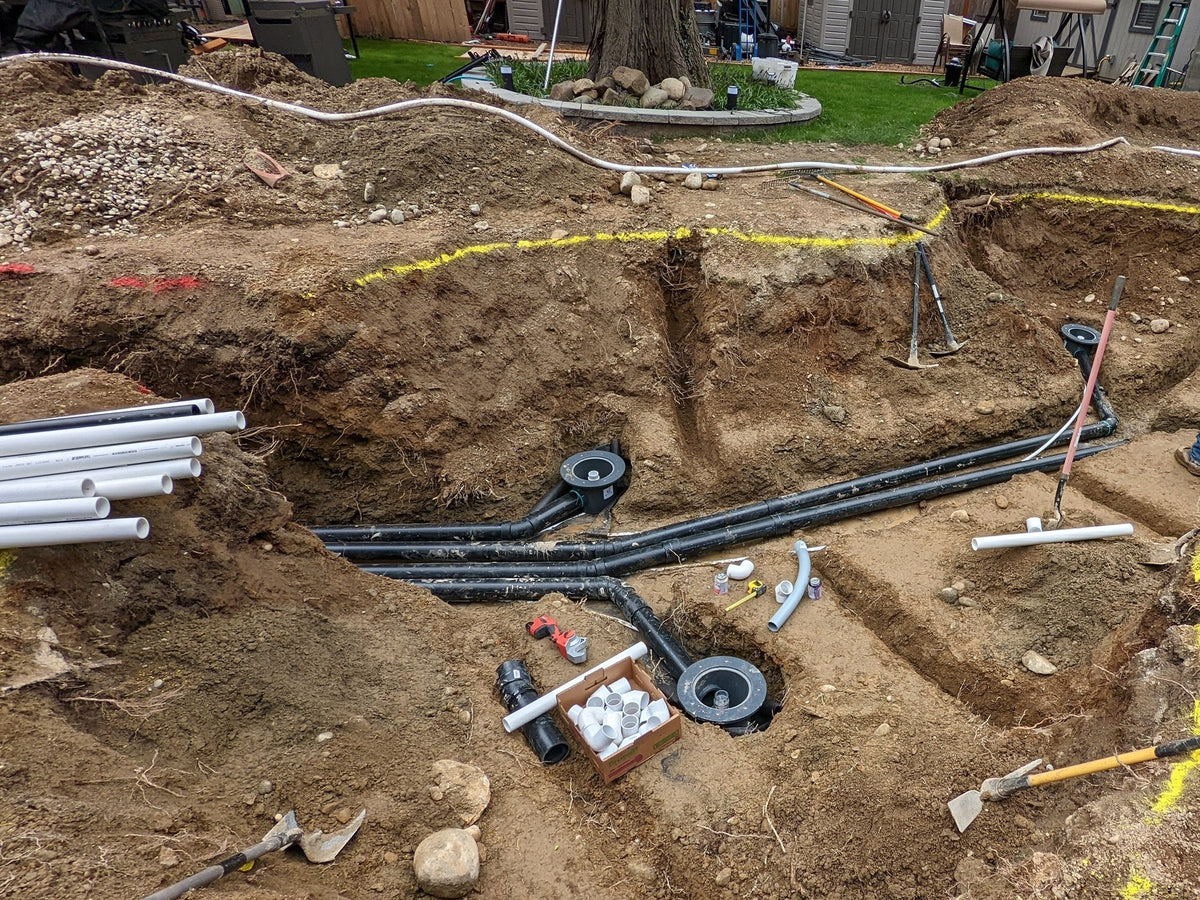 Bottom drains and drain lines plumbed into a newly dug koi pond before the liner goes in